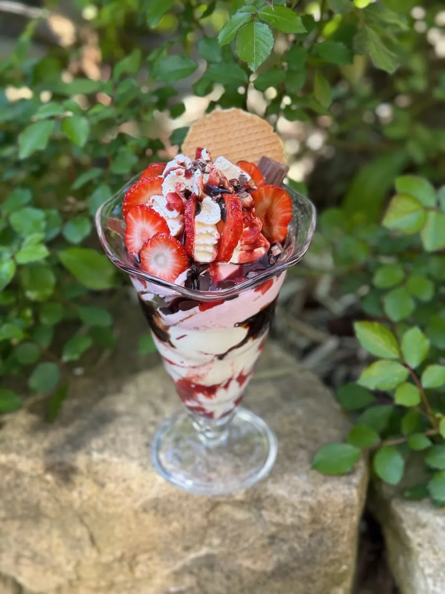 Erdbeer-Eisbecher im hohen Glas mit Schokosauce, Waffel und frischen Erdbeeren