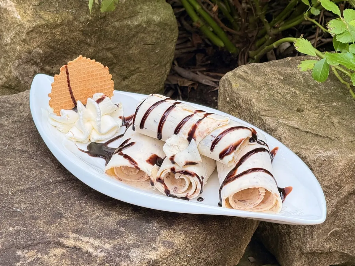 Frisch gerolltes Eis mit Waffel und Schokosauce auf einem Teller