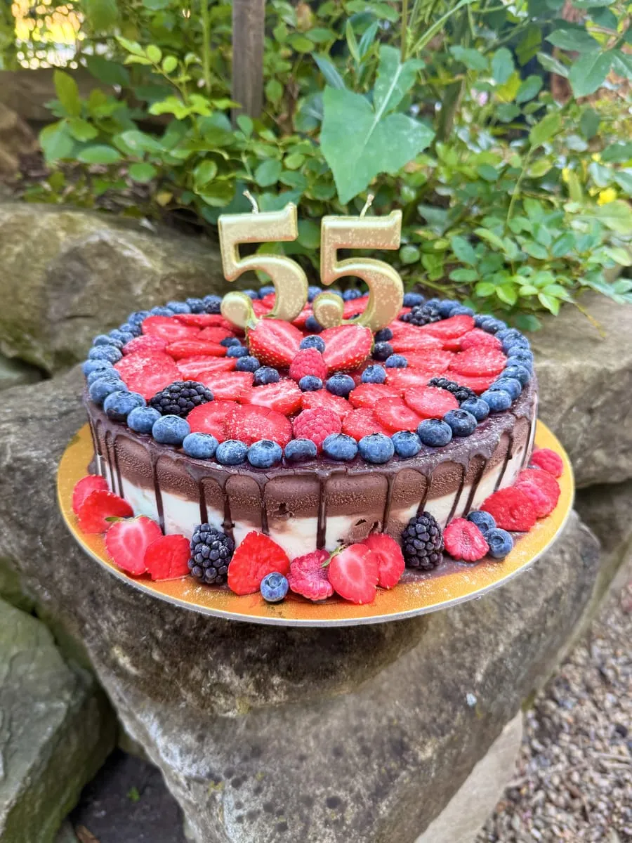 Runde Eistorte mit Schokorand, frischen Beeren und Geburtstagskerzen