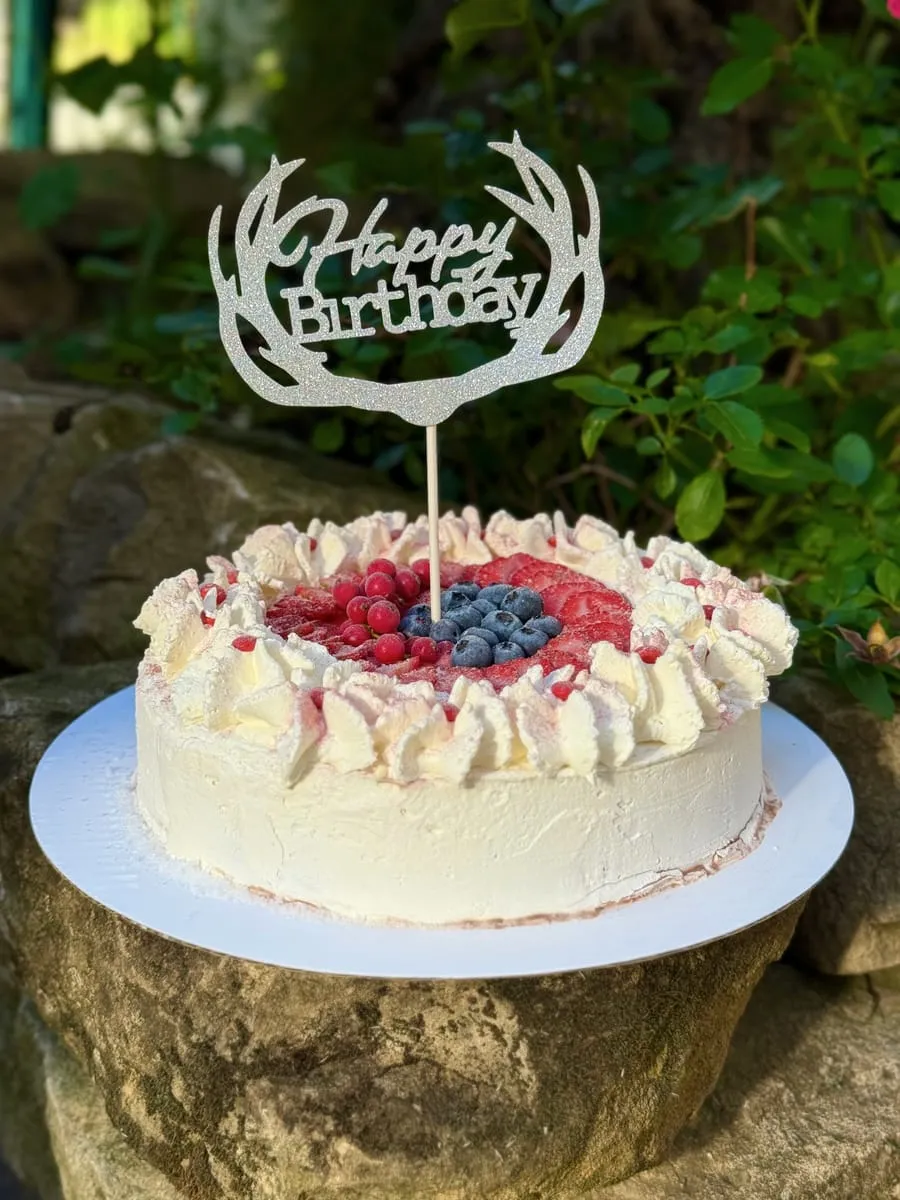 Weiße Eistorte mit Beeren und „Happy Birthday“-Topper